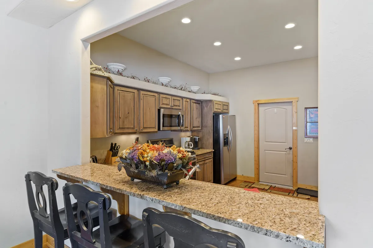 A spacious kitchen with granite countertops, wooden cabinets, stainless steel appliances, and a floral centerpiece. The area is designed for group gatherings, meal prep, and casual conversations, making it ideal for families and friend groups.