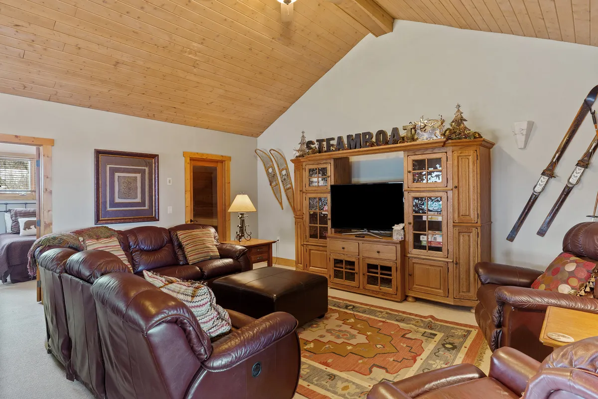 A warm, welcoming living area featuring leather sofas arranged around a coffee table and entertainment center. The setting is ideal for relaxing after a day outdoors, offering ample space for socializing, watching TV, or cozying up with friends and family by the fire.