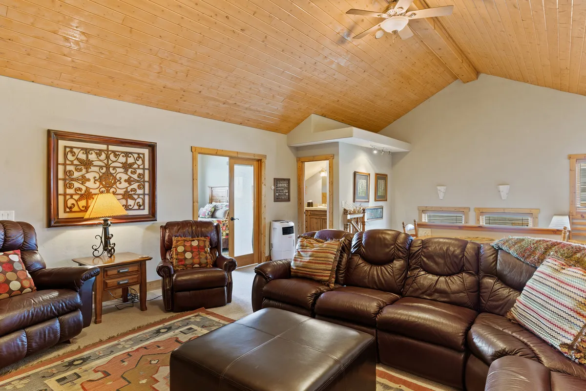 A comfortable seating area with leather chairs, a wooden ceiling, and decorative wall art. The scene suggests a mountain-lodge vibe, ideal for socializing with friends and sharing stories after a day of skiing or snowboarding.