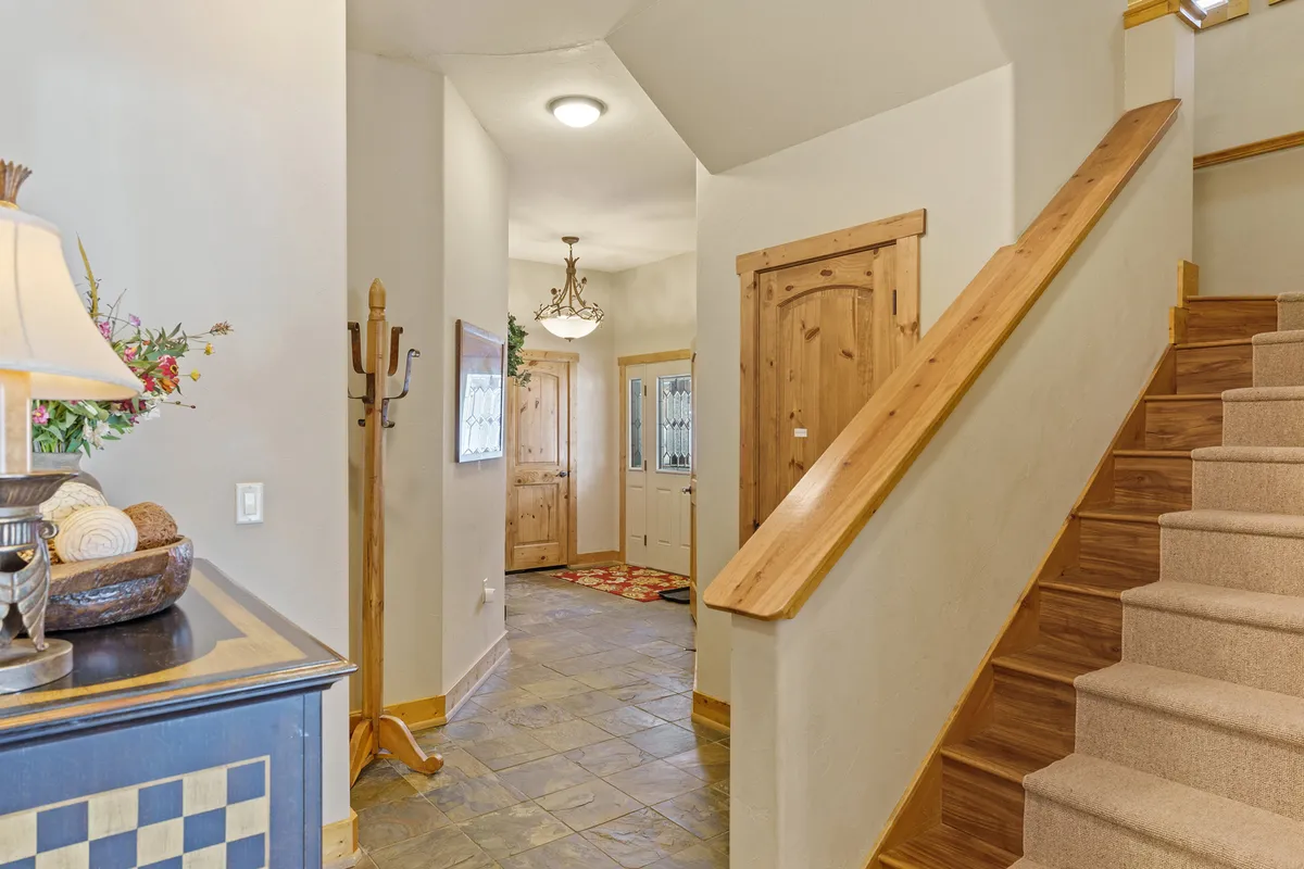 This image captures a warmly lit entrance area featuring a staircase, decorative lamp, and entrance doors. The entryway exudes a sense of arrival and welcome, emphasizing first impressions for guests and the transition from exterior to interior.